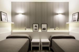 バルセロナにあるレジデンシア ウニヴェルシタリア バルセロナ ディアゴナルのベッド2台、テーブル、照明が備わる客室です。