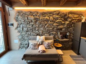 a room with a stone wall with a chair in front at La Casetta in Oyace