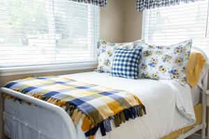 a bed with blue and yellow pillows and a window at Our Little Yellow House in Saint Anthony