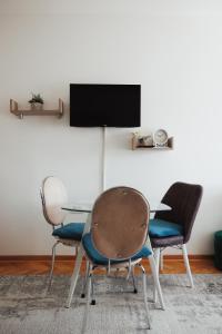 a table with three chairs and a tv on a wall at LUX Apartman Jugi PARKING public free in Novi Pazar