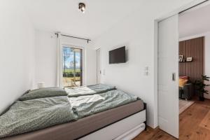 a bedroom with white walls and a bed with a window at BohnApartments Dümmer See Suites, Top Lage 350 m zum See, Balkon, WLAN, Parkplatz in Lembruch