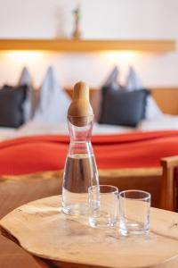 a bottle on a table with two glasses on it at Pension Mayerhofer in Piesendorf