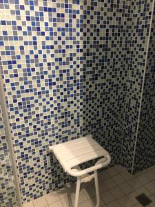 a stool in a bathroom with a tiled wall at Armorique résidence in Malestroit