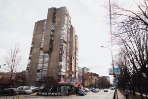 a tall building on a busy city street with cars at LUX Apartman Jugi PARKING public free in Novi Pazar