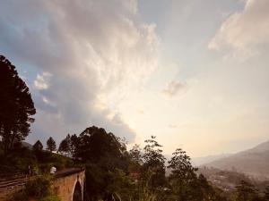 a view of a cloudy sky with trees on a hill at Cinderella three arch view in Ella