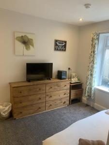 a bedroom with a flat screen tv on a wooden dresser at Camelot Seafront Hotel in Blackpool