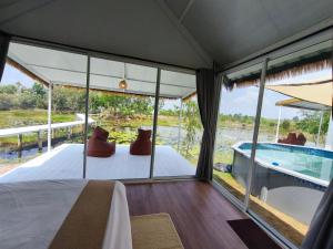 a room with a bed and a view of a body of water at Secret Terrace Pool Villa Rayong in Ban Bua Phut
