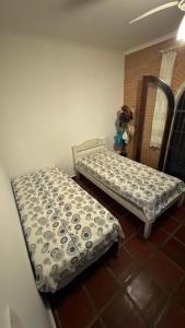 two twin beds in a room with a mirror at Pousada Realeza de Itanhaém in Itanhaém