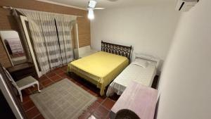 a small room with two beds and a window at Pousada Realeza de Itanhaém in Itanhaém