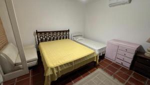 a small bedroom with two beds and a dresser at Pousada Realeza de Itanhaém in Itanhaém