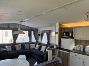 a living room with a blue couch and a kitchen at Haven Caravan Park Cala Gran 3 bedrooms Fleetwood in Fleetwood