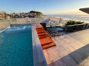 a swimming pool with a bench and the beach at BALUARTE POUSADA in Torres