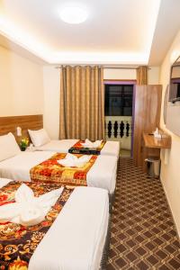 a hotel room with three beds and a window at Al Khaima Hotel in Dubai