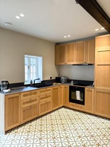a large kitchen with wooden cabinets and a window at Worlaby Coach House in Worlaby