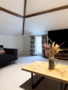 a living room with a table with a vase of flowers on it at Worlaby Coach House in Worlaby