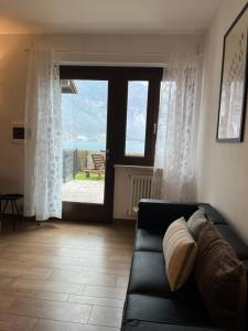 a living room with a couch and a large window at Cà Serena Panoramic Garden - Appartamento Greta in Ledro