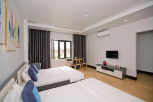 a hotel room with two beds and a television at King House Hotel in Móng Cái