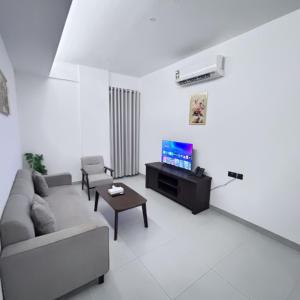 a living room with a couch and a tv at Almasar Hotel in Maţār as Sīb ad Duwalī