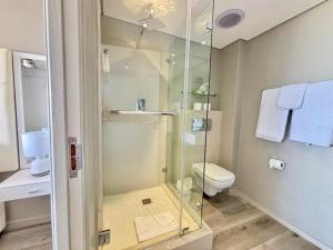a bathroom with a glass shower and a toilet at Relaxing Blouberg Beachfront view Apartment in Cape Town +21 photos