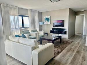 a living room with a white couch and a television at Relaxing Blouberg Beachfront view Apartment in Cape Town