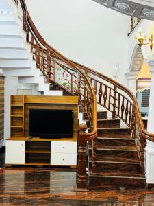 a living room with a staircase and a television at Gem Palace in Perumpāvūr
