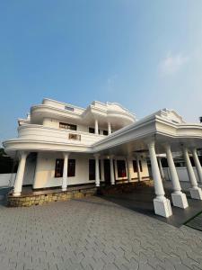 a large white building with a lot of columns at Gem Palace in Perumpāvūr