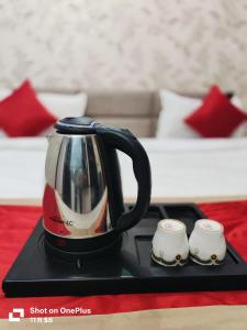 a tea kettle and two cups on a black tray at Hotel Sasa Paradise in Lucknow +9 photos