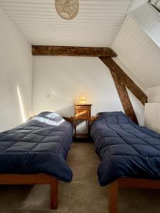 two beds in a attic room with a table at Maison Équilibre in Royère-de-Vassivière