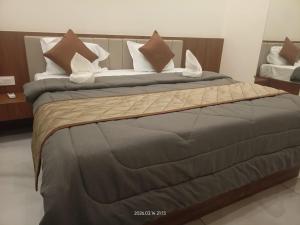 a large bed with brown and white pillows on it at The Nature Park Hotel in Mudhol