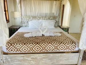 two white swans sitting on top of a bed at Kilele-Retreat Suite in Shela