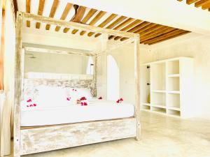 a bedroom with a white bed with red flowers on it at Kilele-Retreat Suite in Shela
