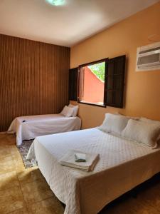 a hotel room with two beds and a window at Espaço Sunshine in Saquarema