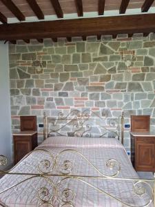 a bed in a room with a stone wall at Casa Al Vento in Lucignano +21 photos