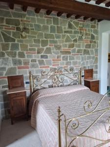 a bedroom with a bed and a stone wall at Casa Al Vento in Lucignano