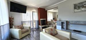 a living room with two chairs and a flat screen tv at Апартамент При Рени in Koprivshtitsa