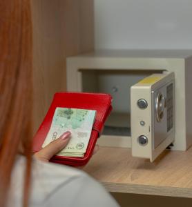 a person holding a cell phone in front of a safe at Hotel Avenida 3 Real en el norte de Cali in Cali