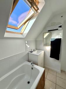 a bathroom with a large white tub and a skylight at Maison Équilibre in Royère-de-Vassivière +18 photos