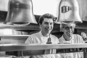 two men are smiling in a kitchen at Hôtel Arcé - Piscine , Padel, Cheminée in Saint-Étienne-de-Baïgorry