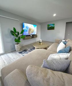 a living room with two couches and a flat screen tv at The Gatehouse Tobago in Buccoo