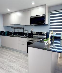 a kitchen with white cabinets and a black counter top at The Gatehouse Tobago in Buccoo