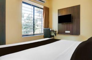 a bedroom with a large bed and a television at POP 84342C Hotel Jashoda in Jodhpur +8 photos