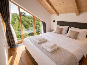 a bedroom with a large bed with a large window at Hiša PRI JEZERU in Dobrovnik