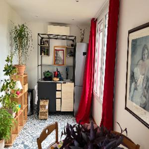a living room with a refrigerator and red curtains at À l'ombre du mûrier in Blauvac