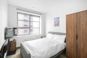 a bedroom with a bed with a wooden cabinet and a television at Cozy and Spacious Central London room in Canary Wharf Flat with a City View & a Private Bathroom in London