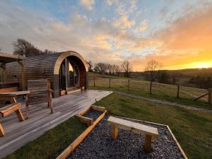 a wooden deck with benches and a gazebo at Four Paws Glamping in Aberystwyth