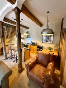 a living room with a leather couch and a kitchen at The old stables at flass in Maulds Meaburn