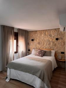 a bedroom with a large bed and a stone wall at La Rambla in Albarracín