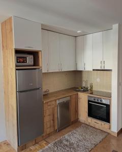 a kitchen with white cabinets and a stainless steel refrigerator at Apartment Tramonto Budva in Budva