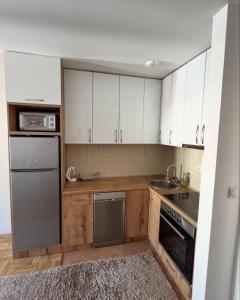 a kitchen with white cabinets and a stainless steel refrigerator at Apartment Tramonto Budva in Budva