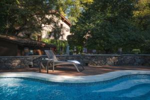 a chair and a table next to a swimming pool at Hotel Can Blanc in Olot